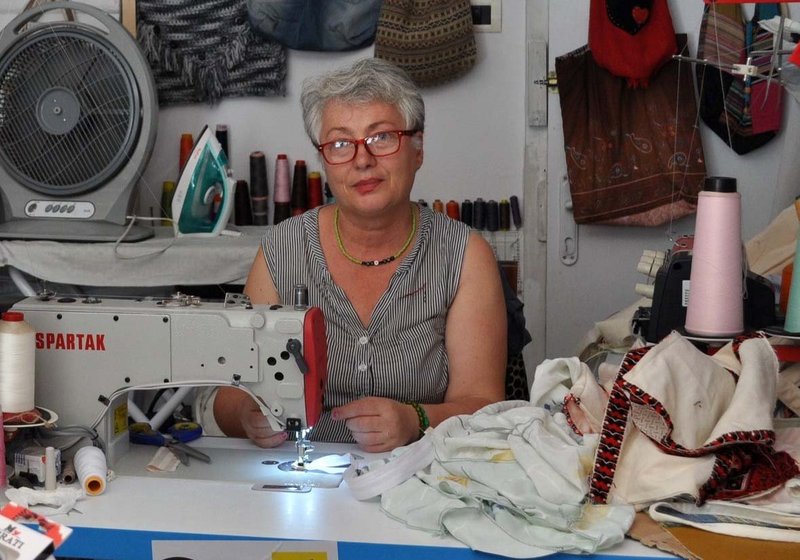 Eine Näherin in Albanien sitzt an ihrer Nähmaschine, die sie dank der Förderung von Help anschaffen konnte.