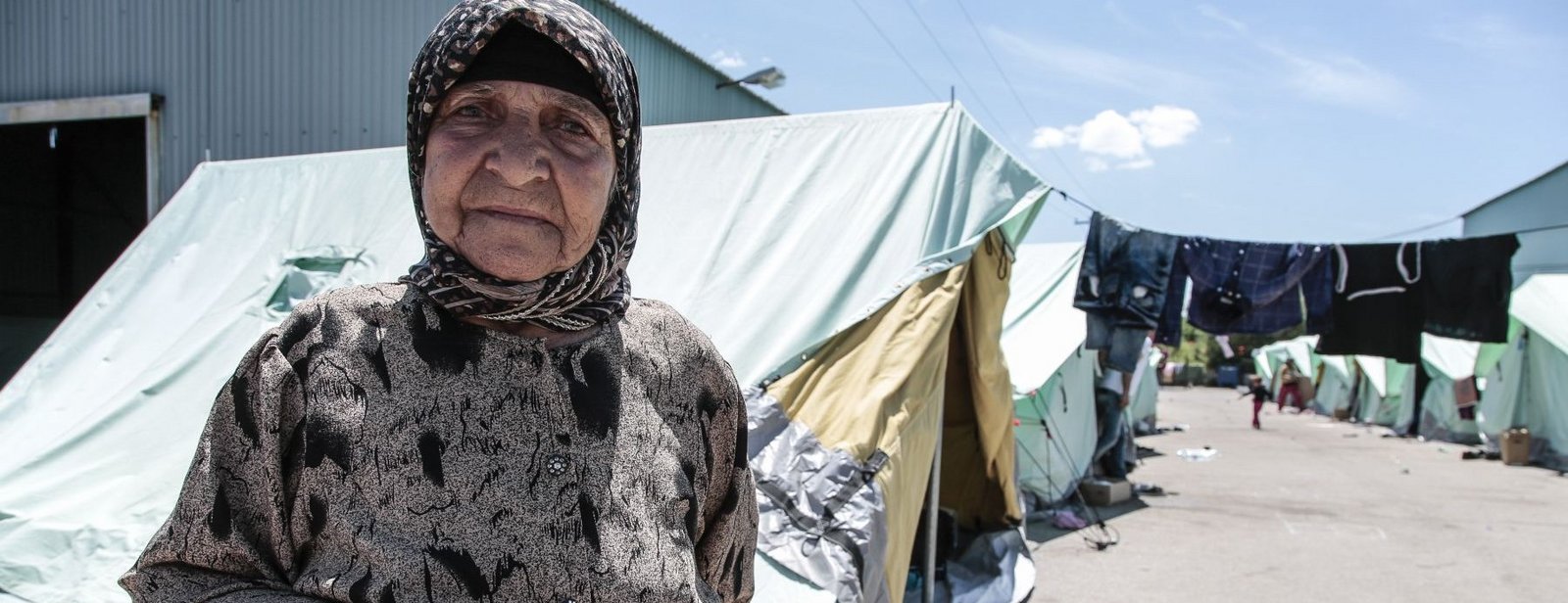 Alte Frau vor einem Zeltlager in Griechenland