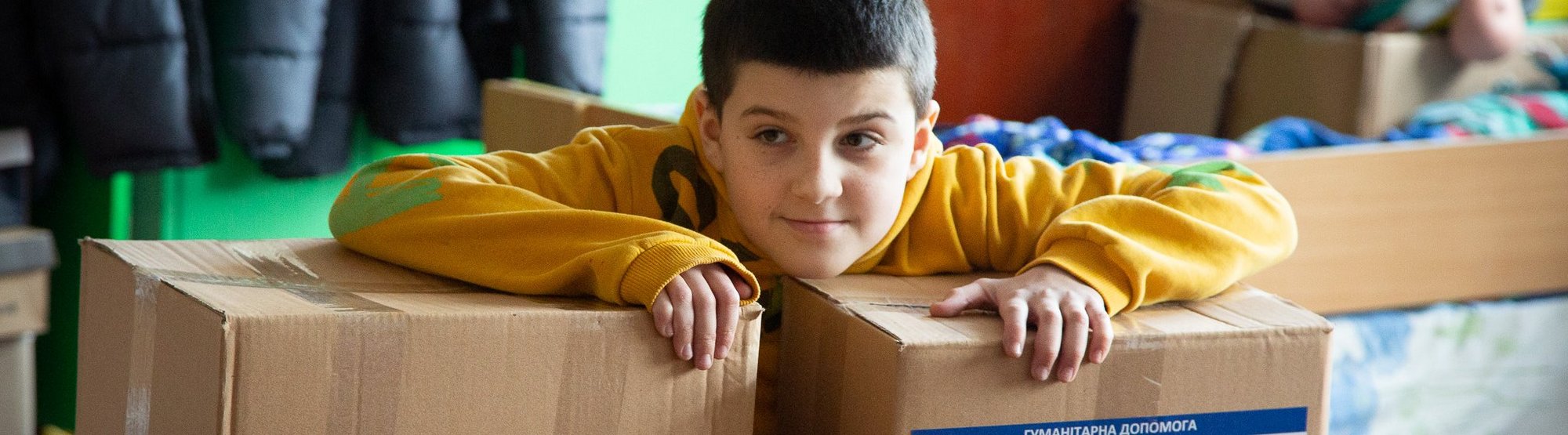 Kind mit Hilfspaketen Jahrestag Ukraine Krieg