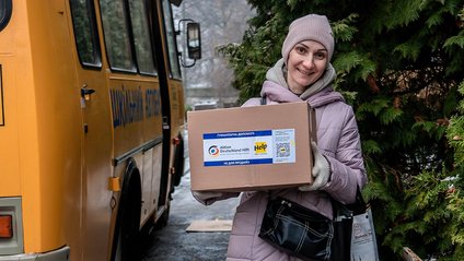 Eine lächelnde Ukrainerin mit einem Help-Hilfspaket