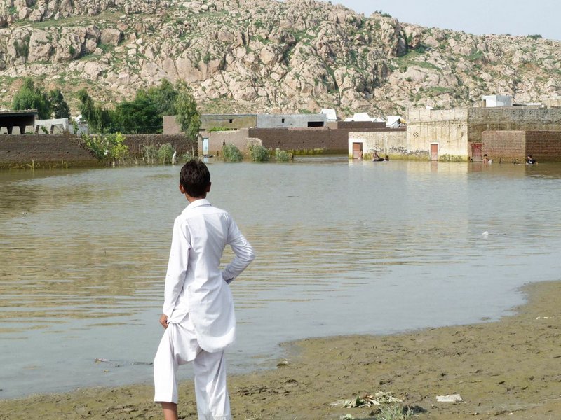 Ein Mann blickt auf ein überschwemmtes Dorf in Pakistan