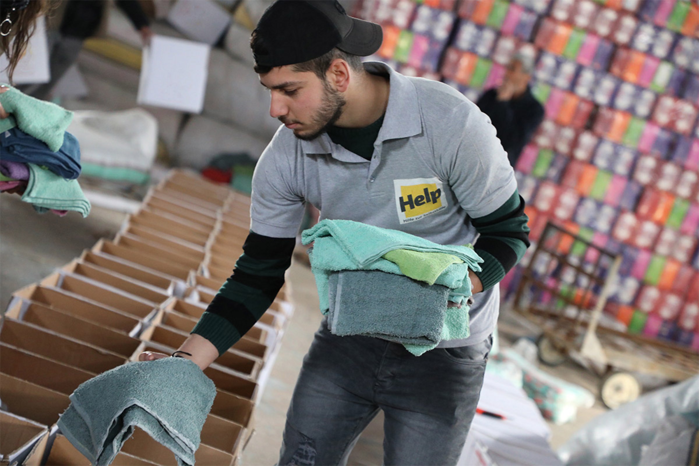 Ein Help-Mitarbeiter packt Handtücher in Hygienepakete