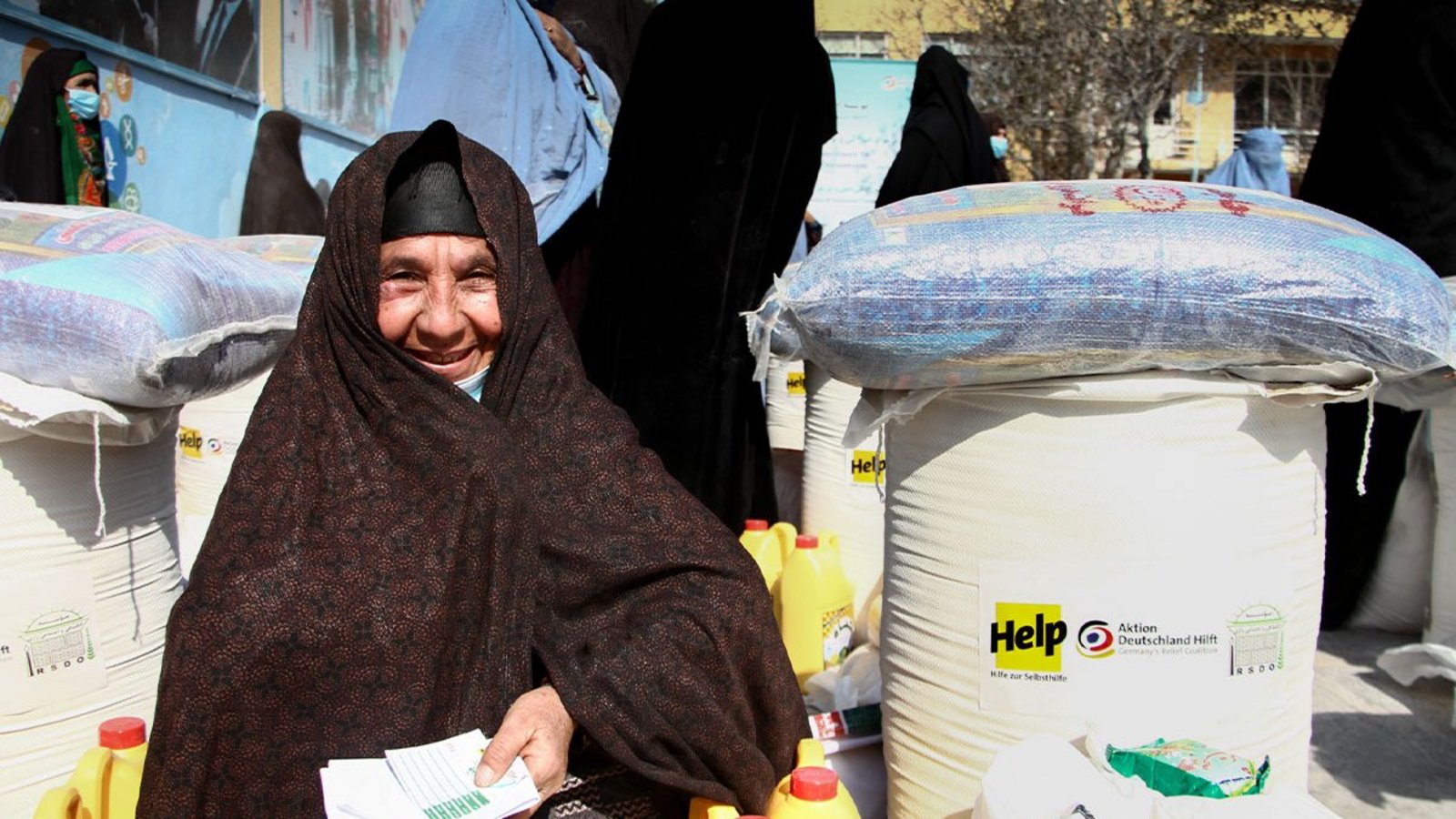 Eine afghanische Frau freut sich über die Lebensmittelhilfe von Help