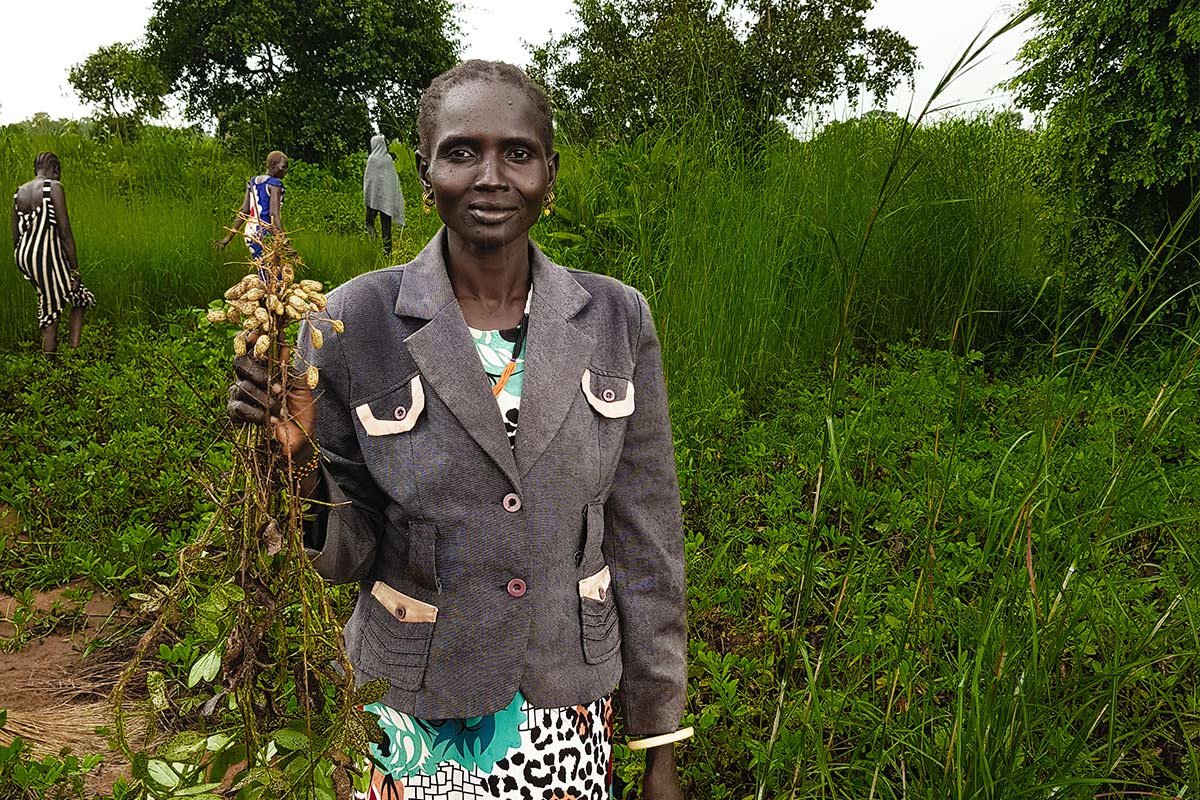 Eine südsudanesische Kleinbäuerin hält frisch geerntete Erdnüsse in die Kamera