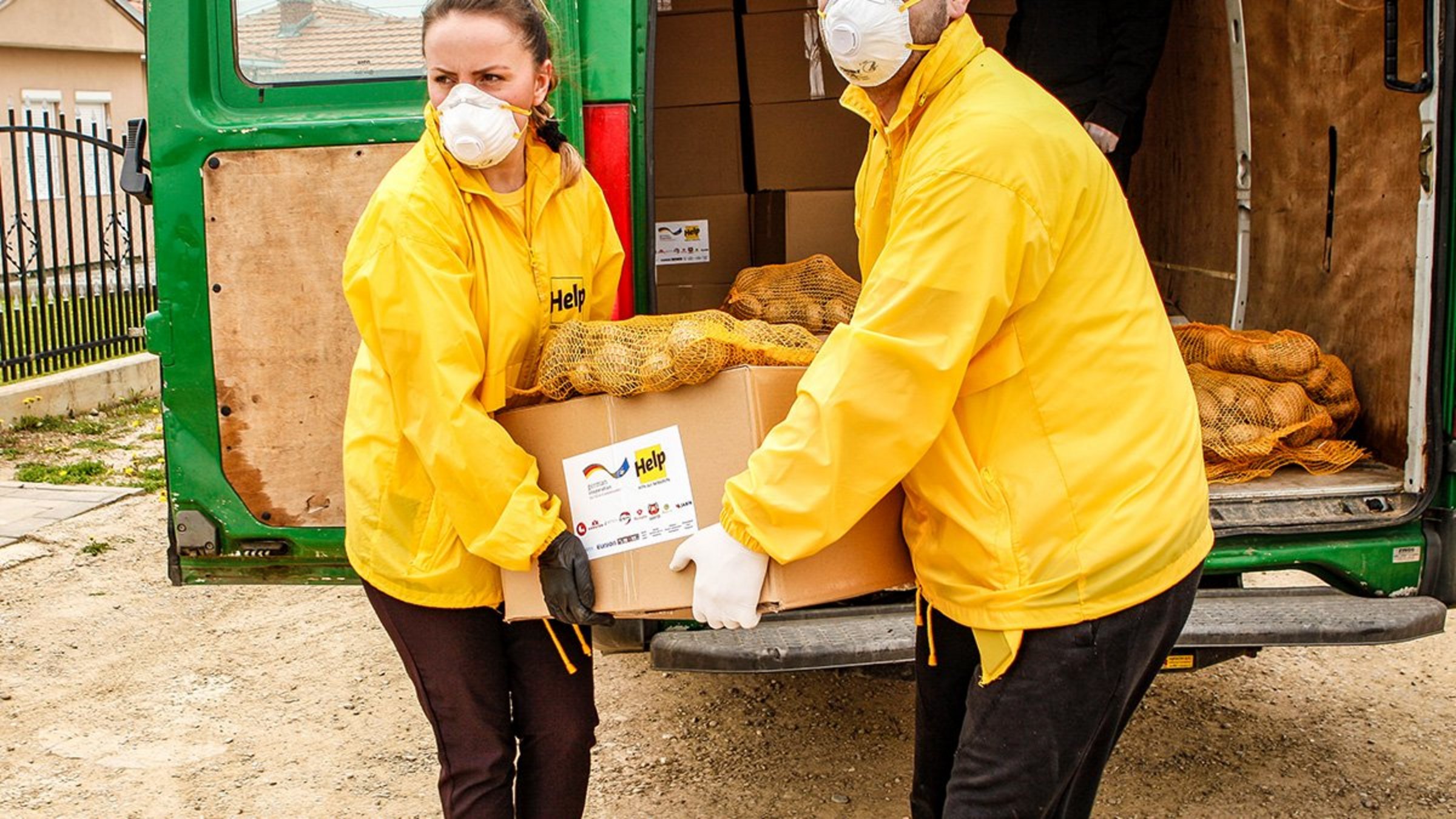 Zwei Help-Mitarbeiter verteilen Lebensmittelpakete im Kosovo