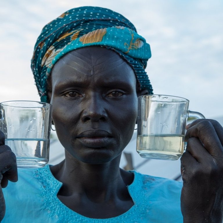 Frau mit zwei Gläsern mit sauberem und dreckigem Wasser in der Hand