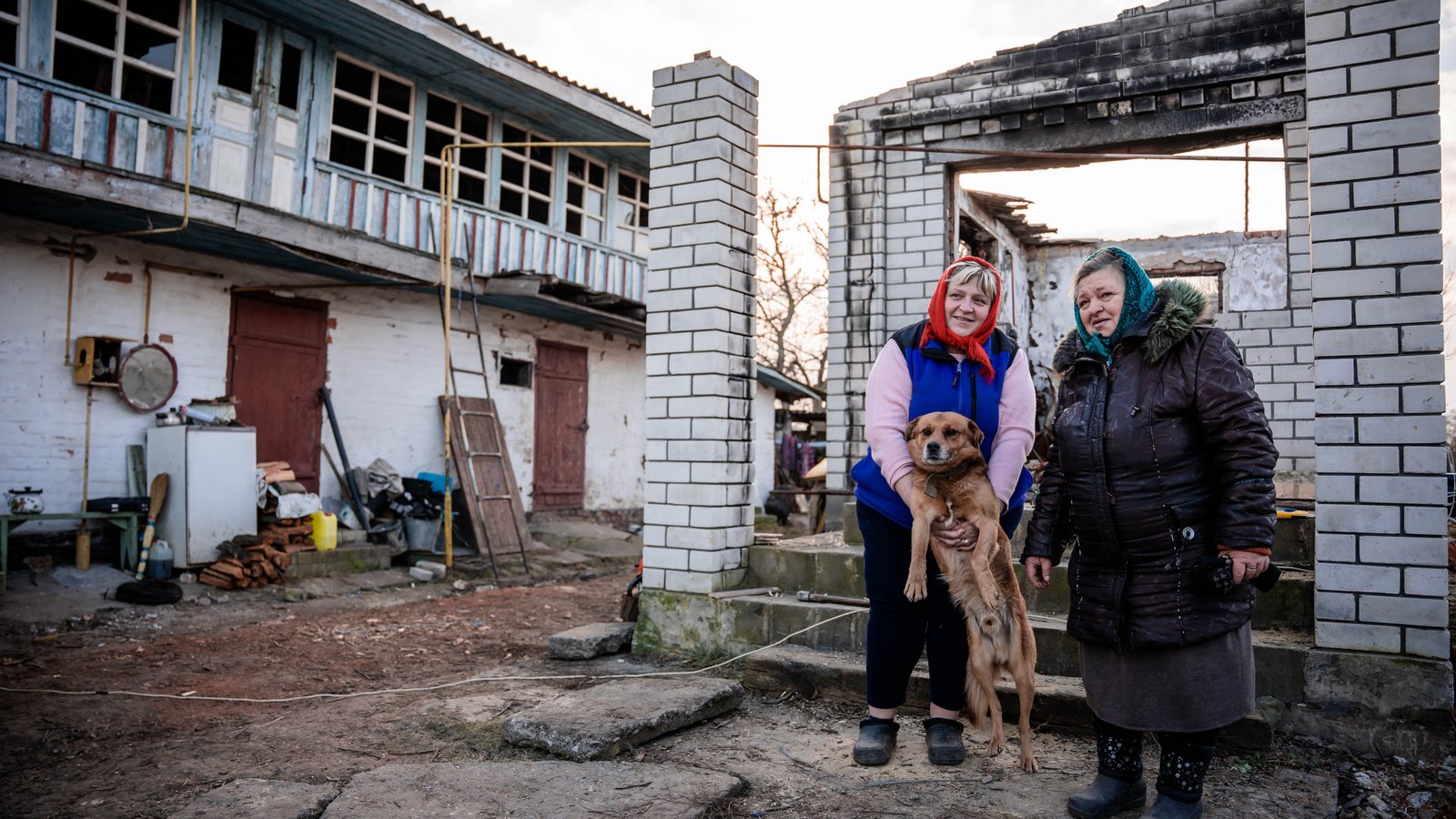 Zwei Frauen stehen vor zerstörtem Gebäude
