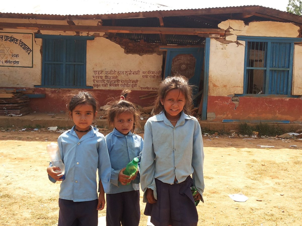 Nepaesische Mädchen vor ihrer zerstörten Schule