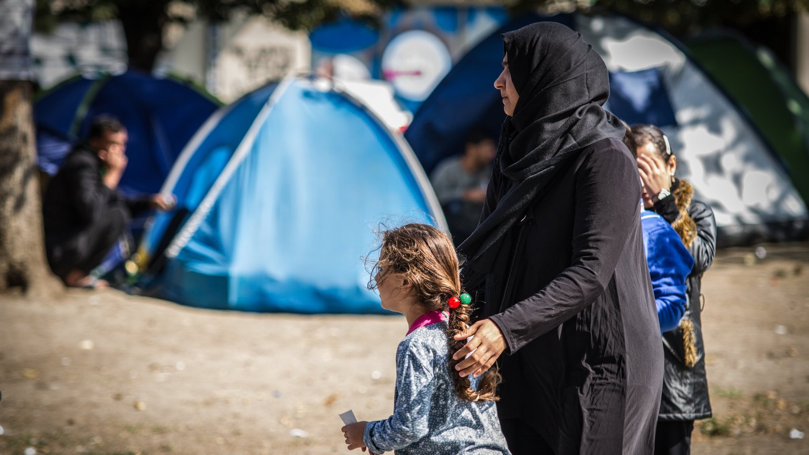 Mutter und Töchter vor Flüchtlingszelten