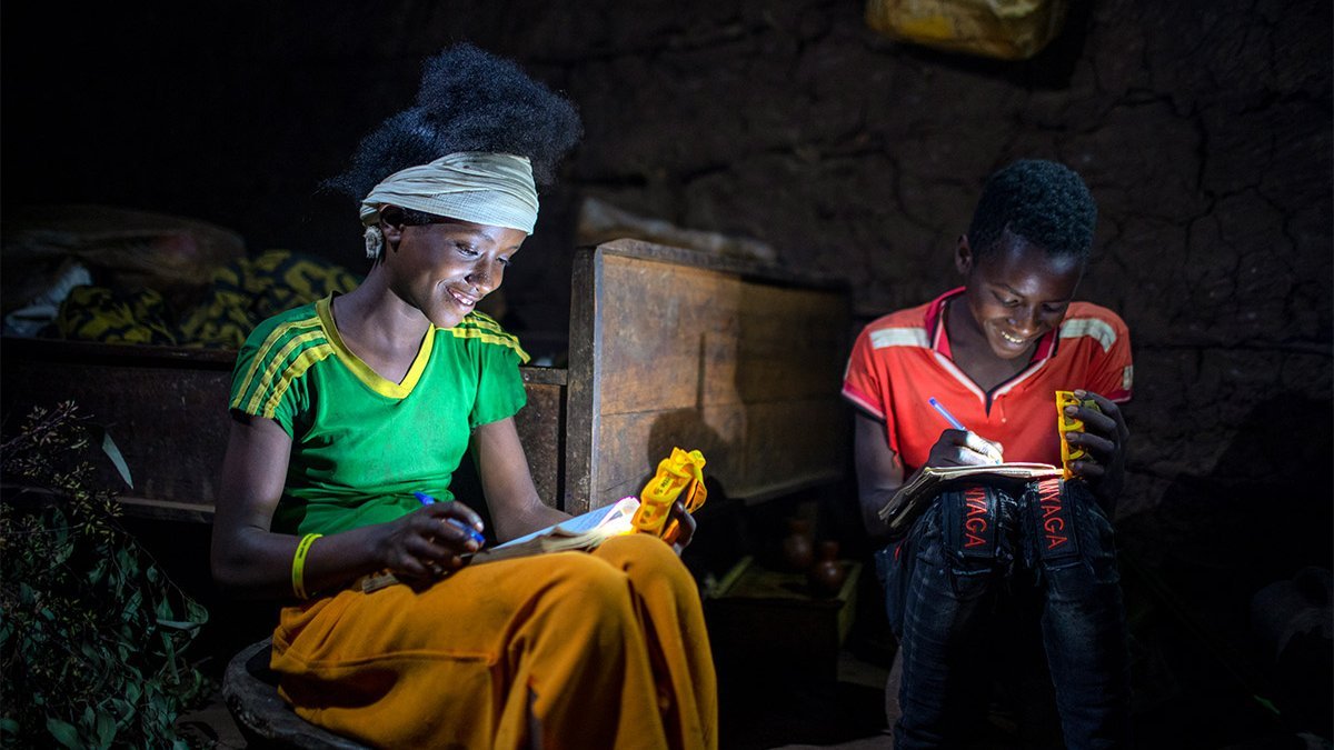 Ein Mädchen und ein Junge lesen im Dunkeln mit Little Sun-Solarlampen