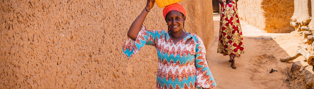 Frau aus Mali trägt Wasserkanister