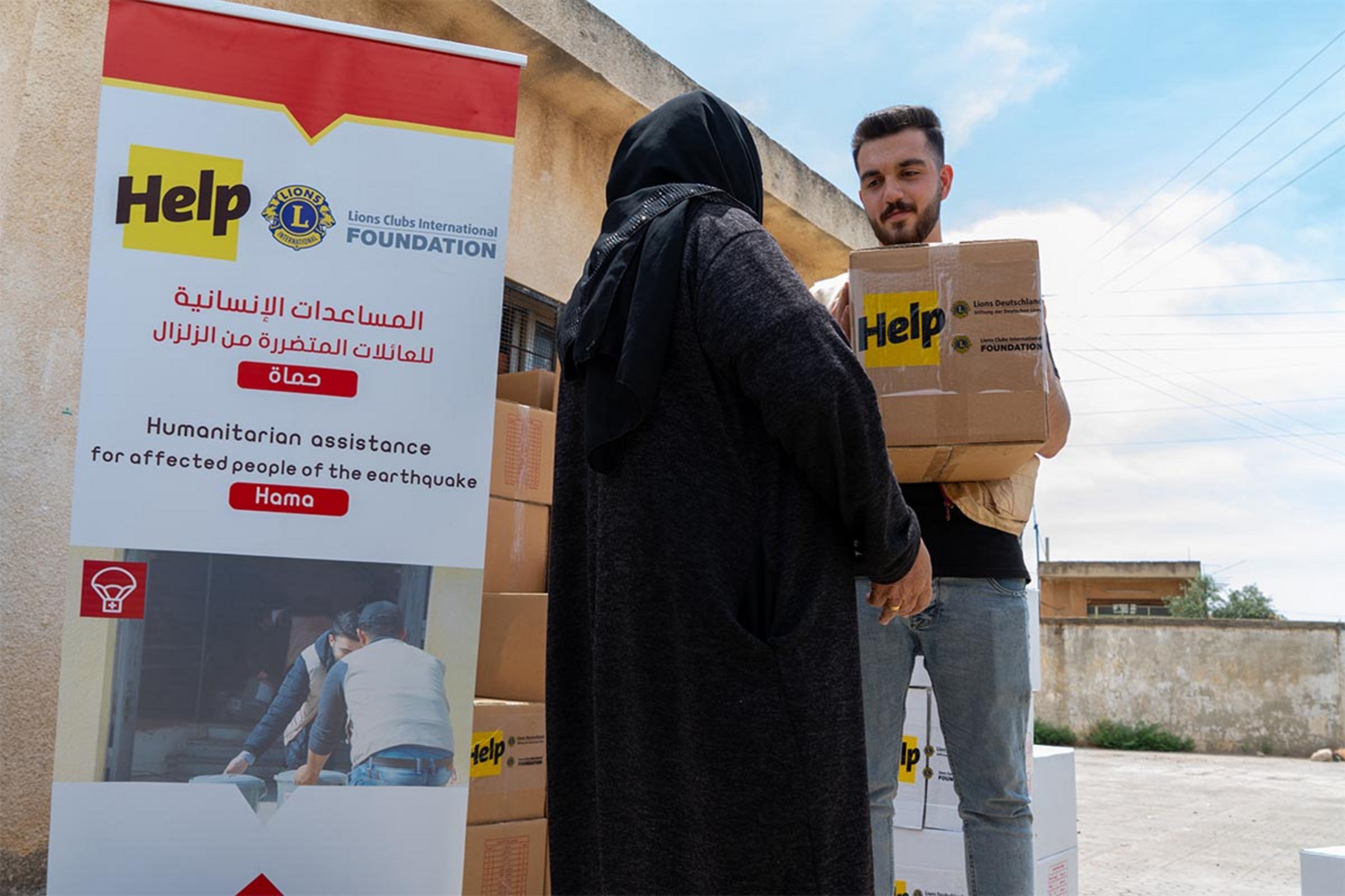 Eine syrische Frau erhält ein Hilfspaket von Help