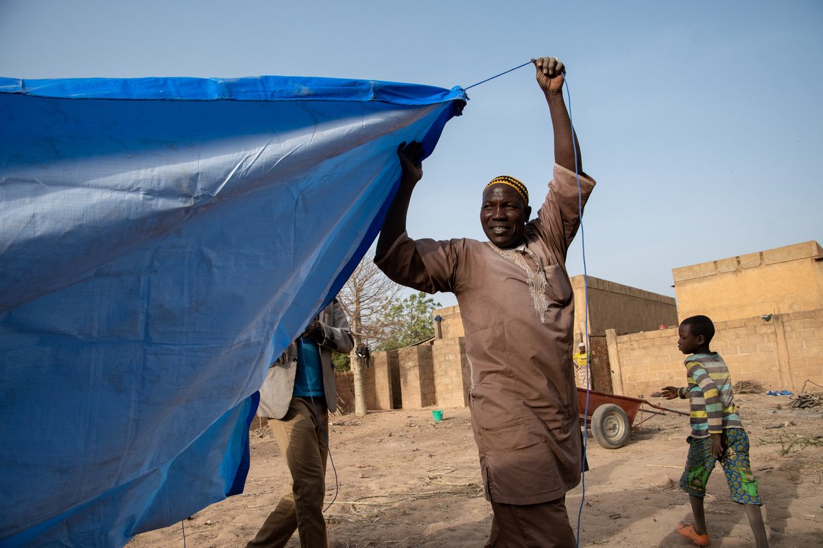 Ein geflüchteter Mann aus Burkina Faso beim Aufbau eines Zeltes, das als Notunterkunft dient