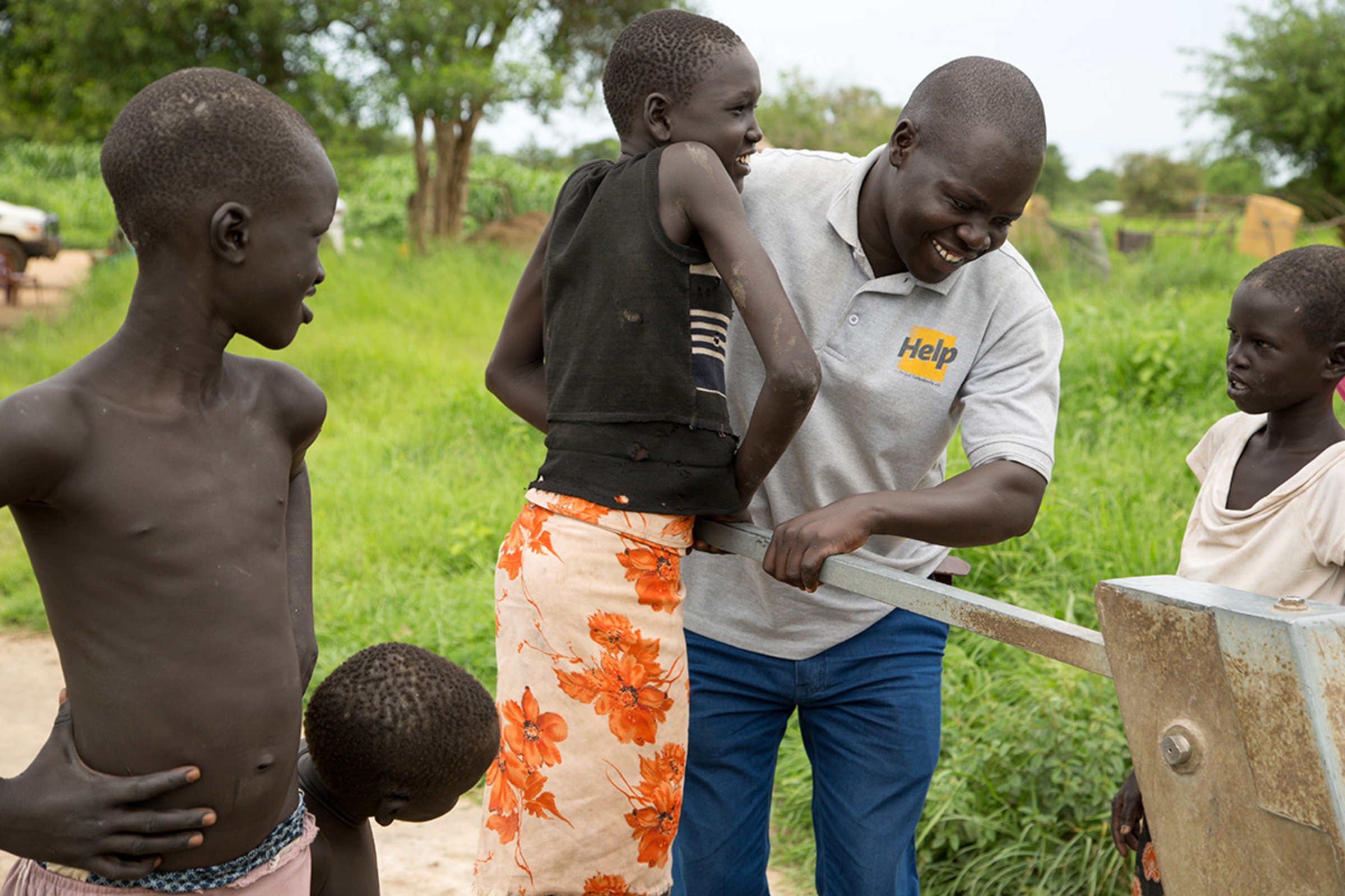Ein Mitarbeiter von Help und ein Junge pumpen gemeinsam Wasser an einem Brunnen im Südsudan