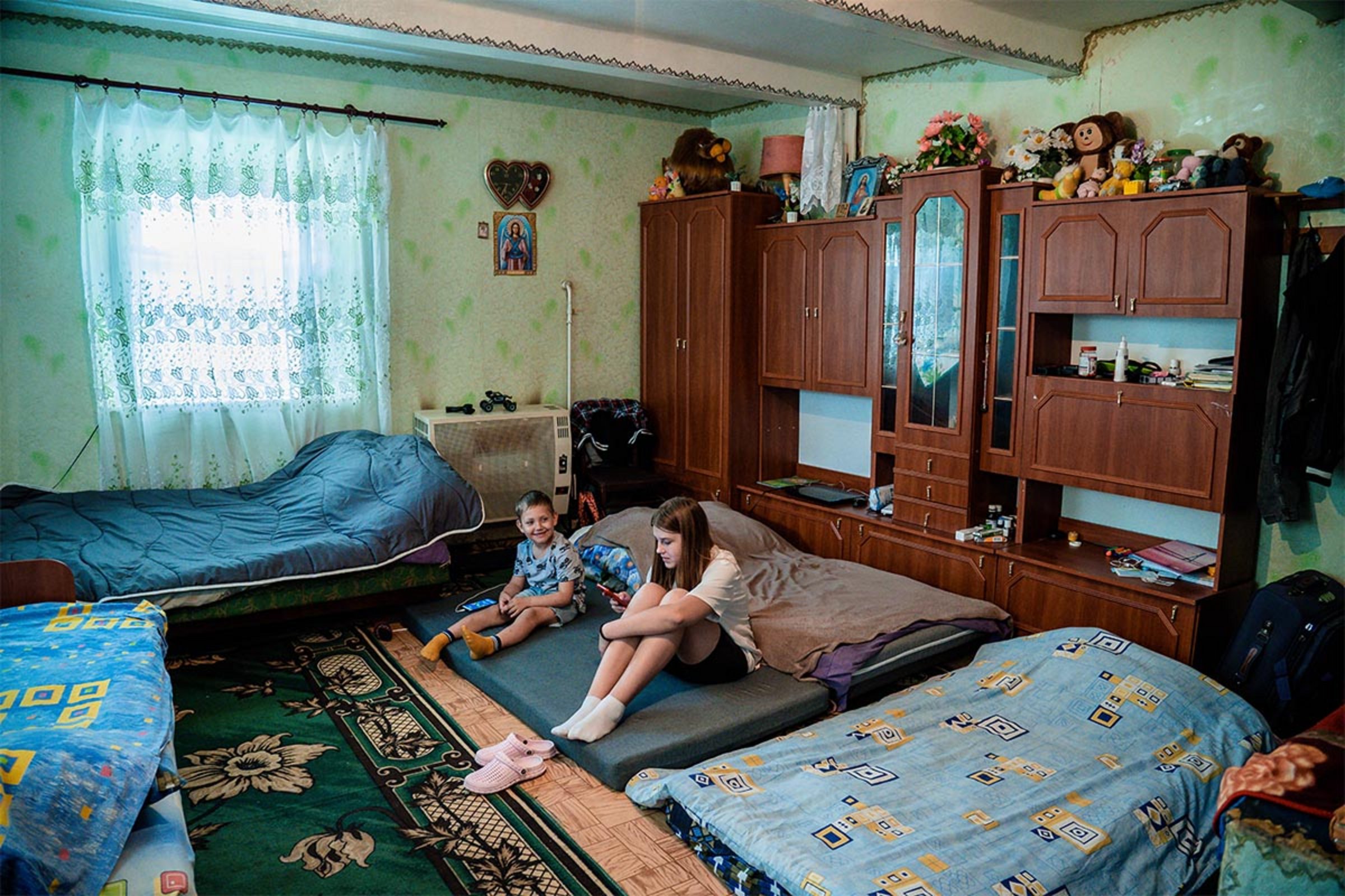 Zwei Kinder sitzen auf Matratzen in einem Wohnzimmer