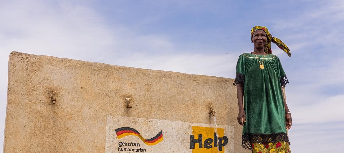 Eine Frau steht vor einem Brunnen in Mali, den Help errichtet hat