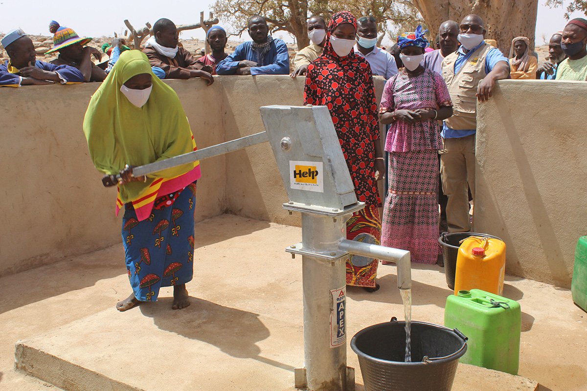 Eine Frau aus Mali pumpt Wasser am Brunnen, den Help gebaut hat
