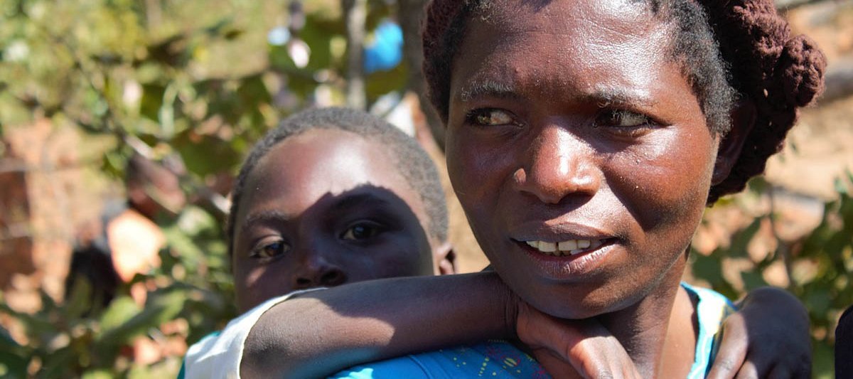 Eine junge Frau in Malawi mit ihrem Kind auf dem Rücken