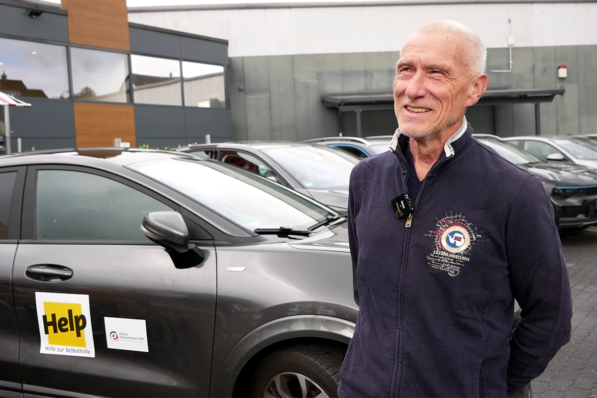 Der ehrenamtliche Fahrer Johann Enders steht vor einem der Wagen der Charity Alliance.