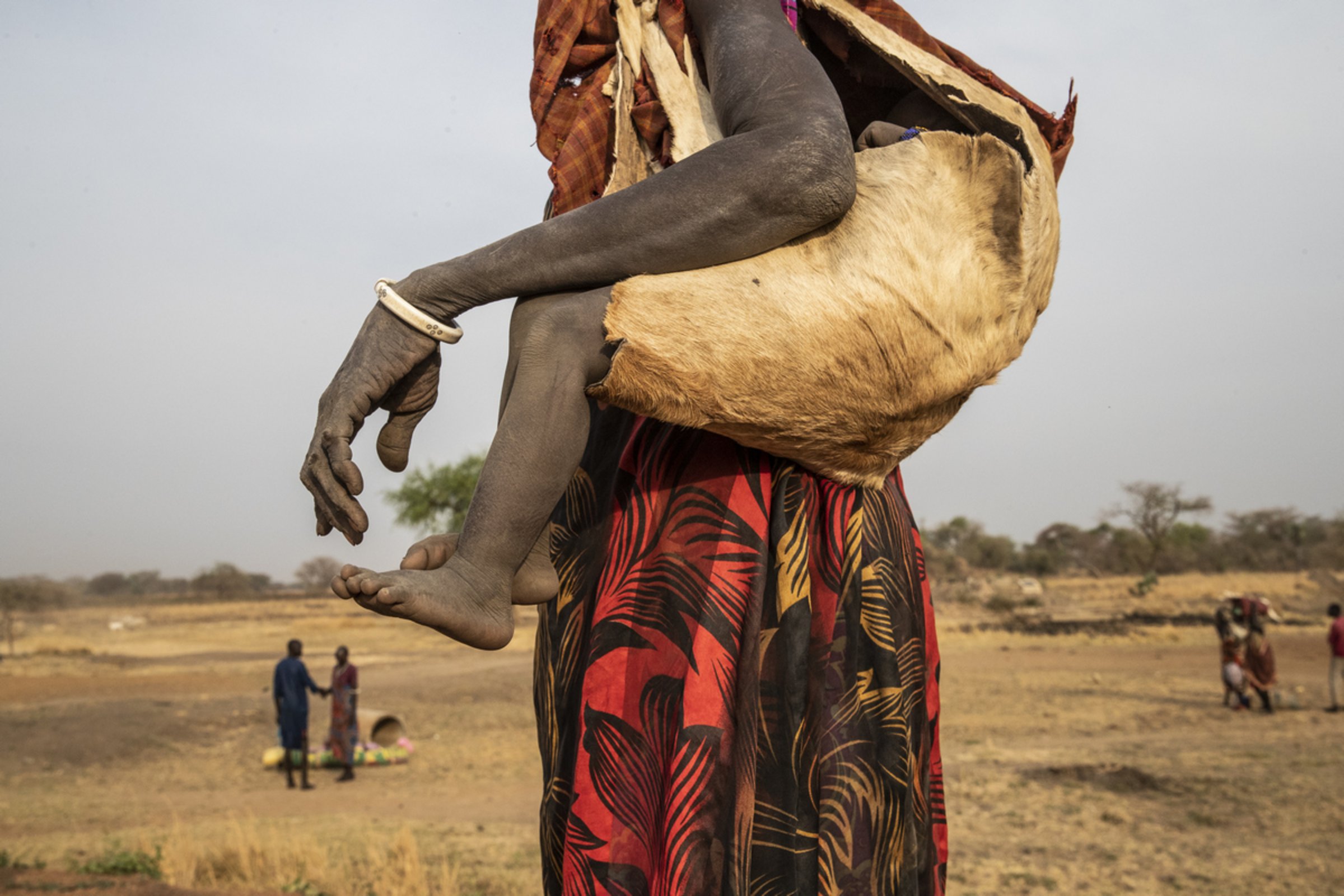 Eine Frau transportiert ihr Kind in einer Tasche aus Ziegenhaut.