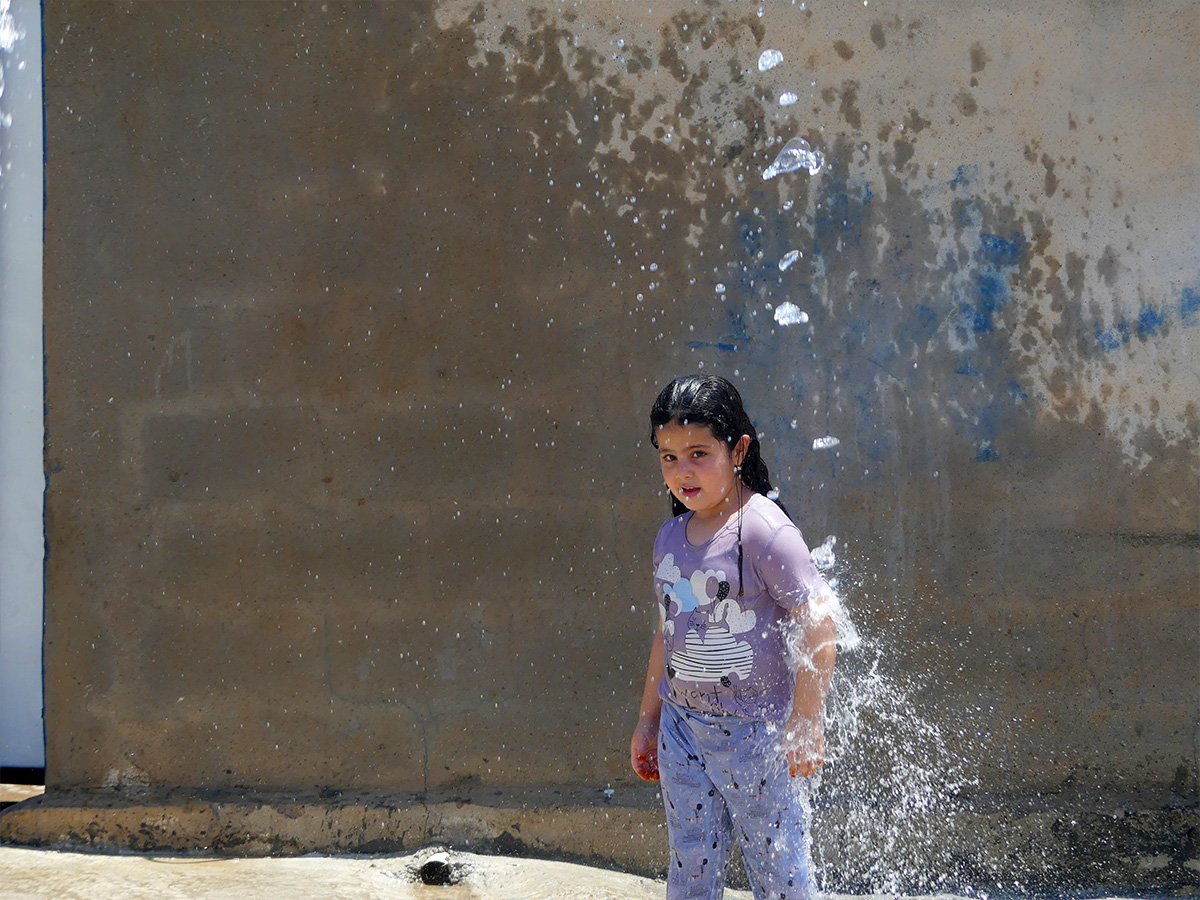 Mädchen im Irak wird mit Wasser nassgespritzt