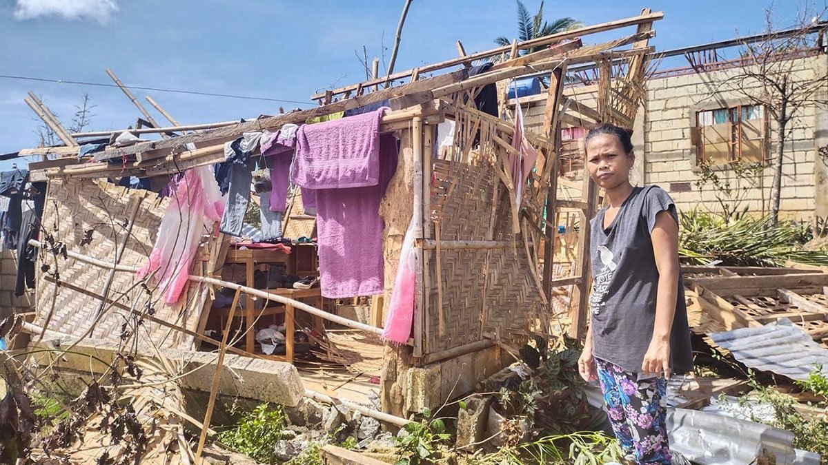 Eine Frau auf den Philippinen steht vor ihrem zerstörten Haus