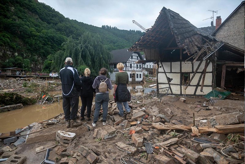Eine Familie steht vor weggerissenen Häusern in Ahrweiler nach der Hochwasser-Katastrophe.