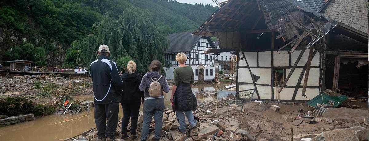 Eine Familie steht nach der Flutkatastrophe vor weggerissenen Häusern in Ahrweiler.