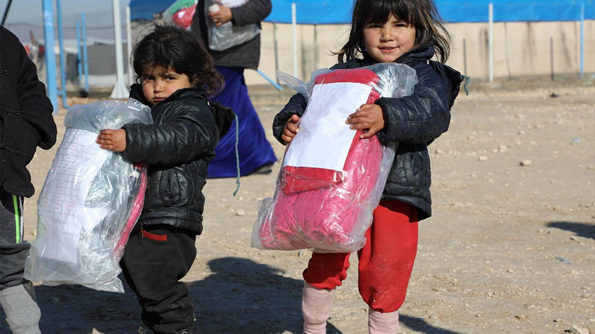 Zwei kleine Mädchen halten Winterkleidung von Help in der Hand