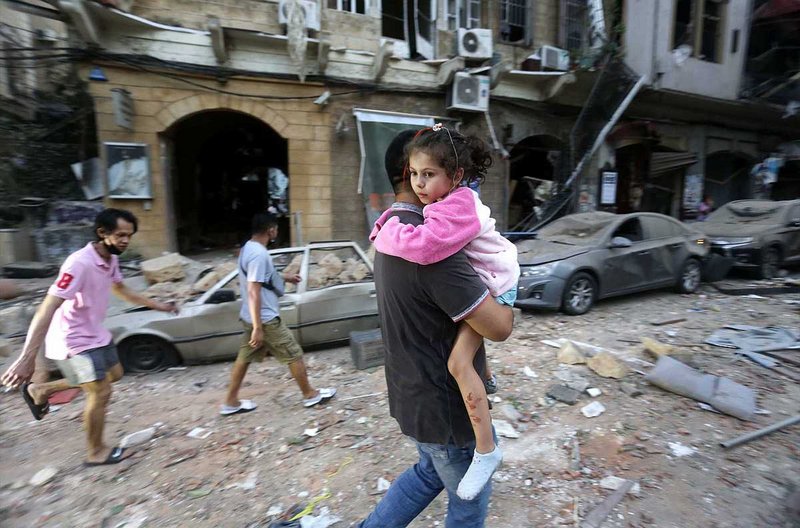 Ein Vater trägt seine Tochter durch die zerstörten Straßen Beiruts