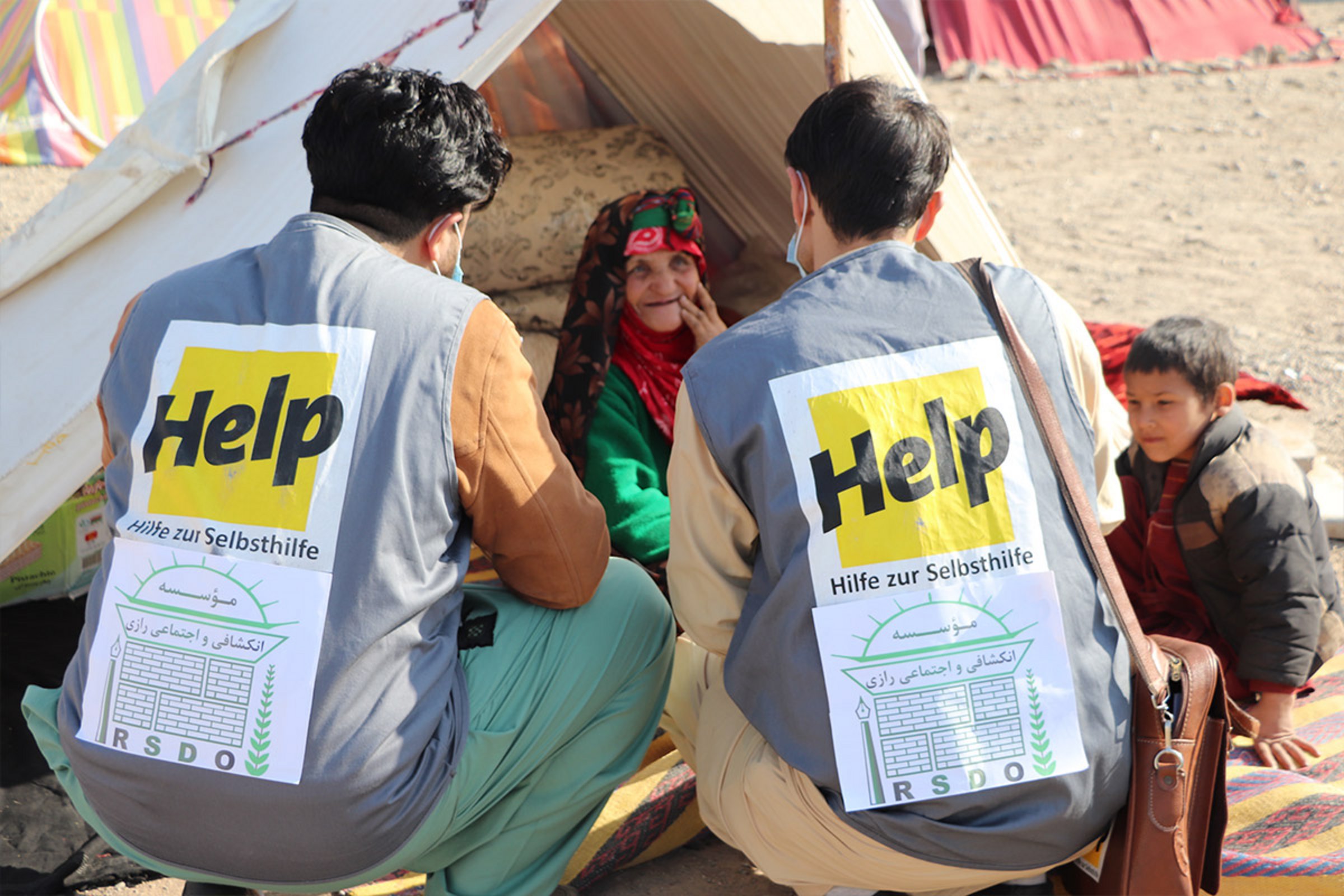 Zwei Help-Mitarbeiter interviewen eine Frau in ihrem Flüchtlingszelt am Rande der Stadt Herat.