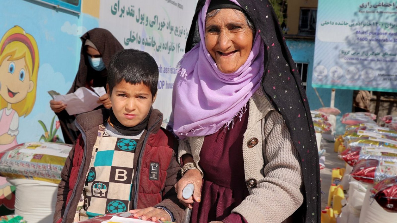 Eine afghanische Frau und ihr Sohn erhalten Lebensmittelhilfe von Help