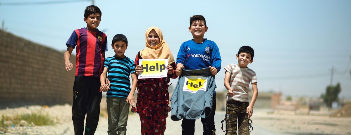 Springende Kinder im Irak mit Help Logos in den Händen
