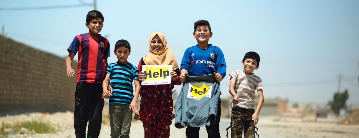 Springende Kinder im Irak mit Help Logos in den Händen
