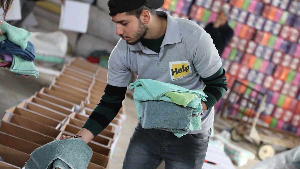 Ein Help-Mitarbeiter packt Handtücher in Hygienepakete