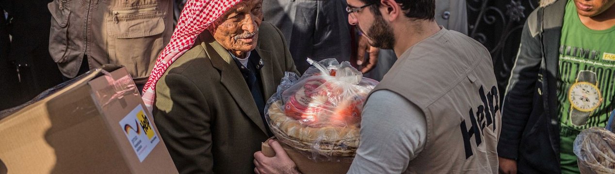 Jordanischer Mann erhält Lebensmittelpaket von Help-Mitarbeiter