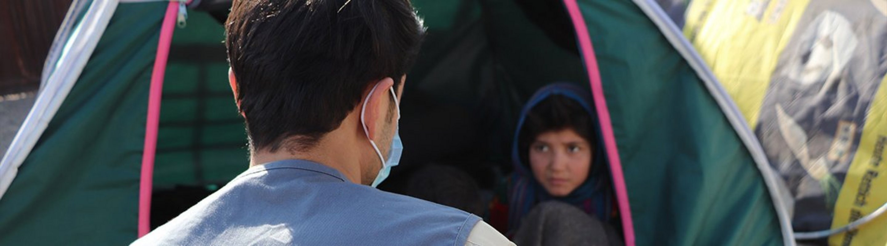 Ein Help-Mitarbeiter sitzt vor dem Zelt einer afghanischen Flüchtlingsfamilie