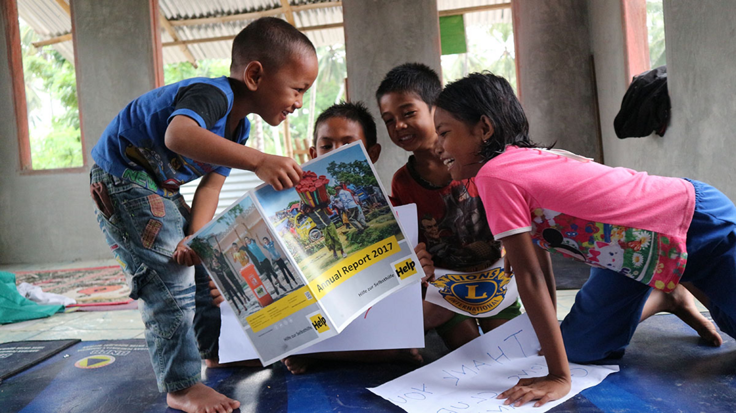 Vier Kinder schauen sich den Jahresbericht von Help an
