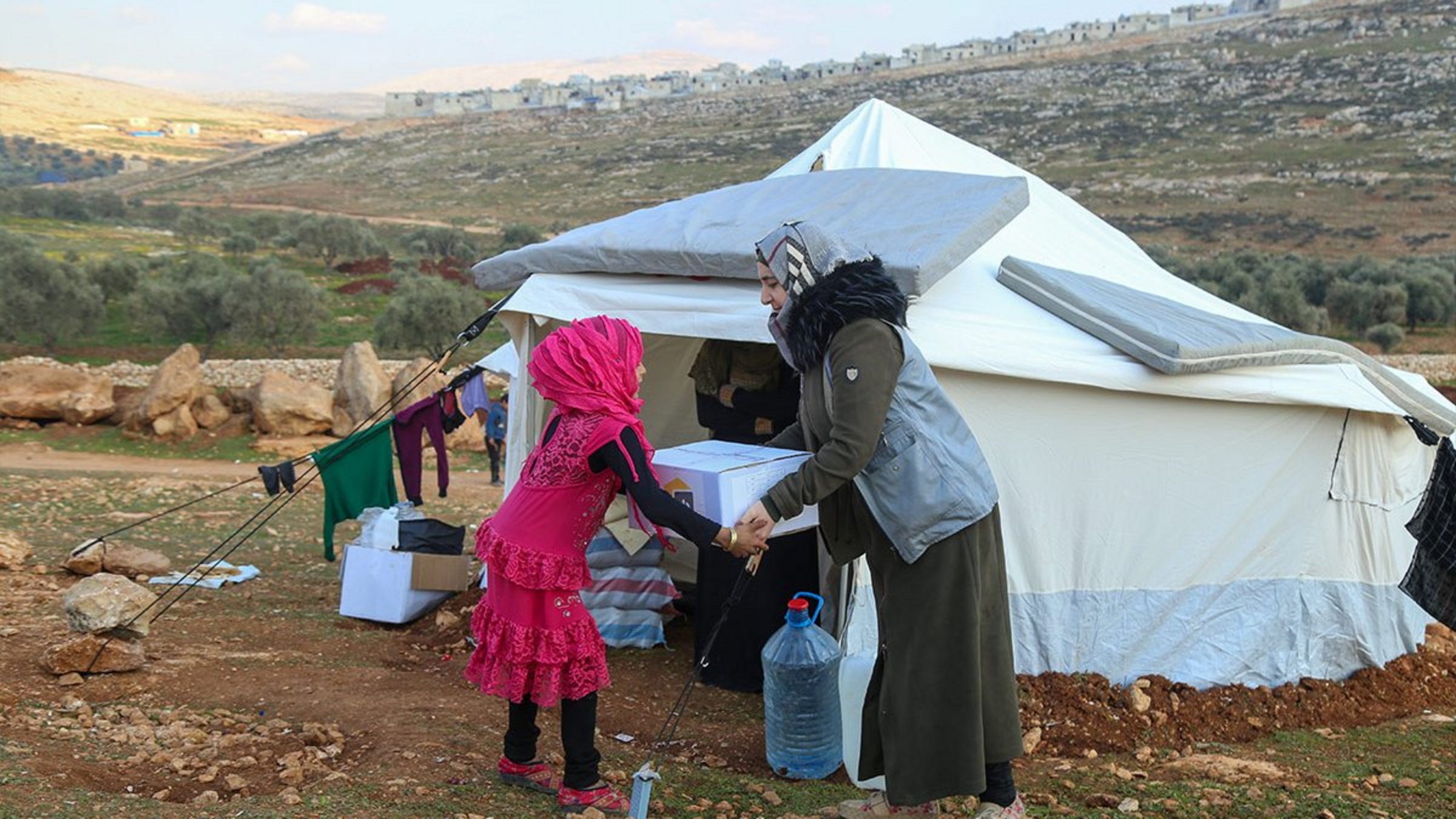 Eine Helferin überreicht einem syrischen Mädchen Hilfsgüter