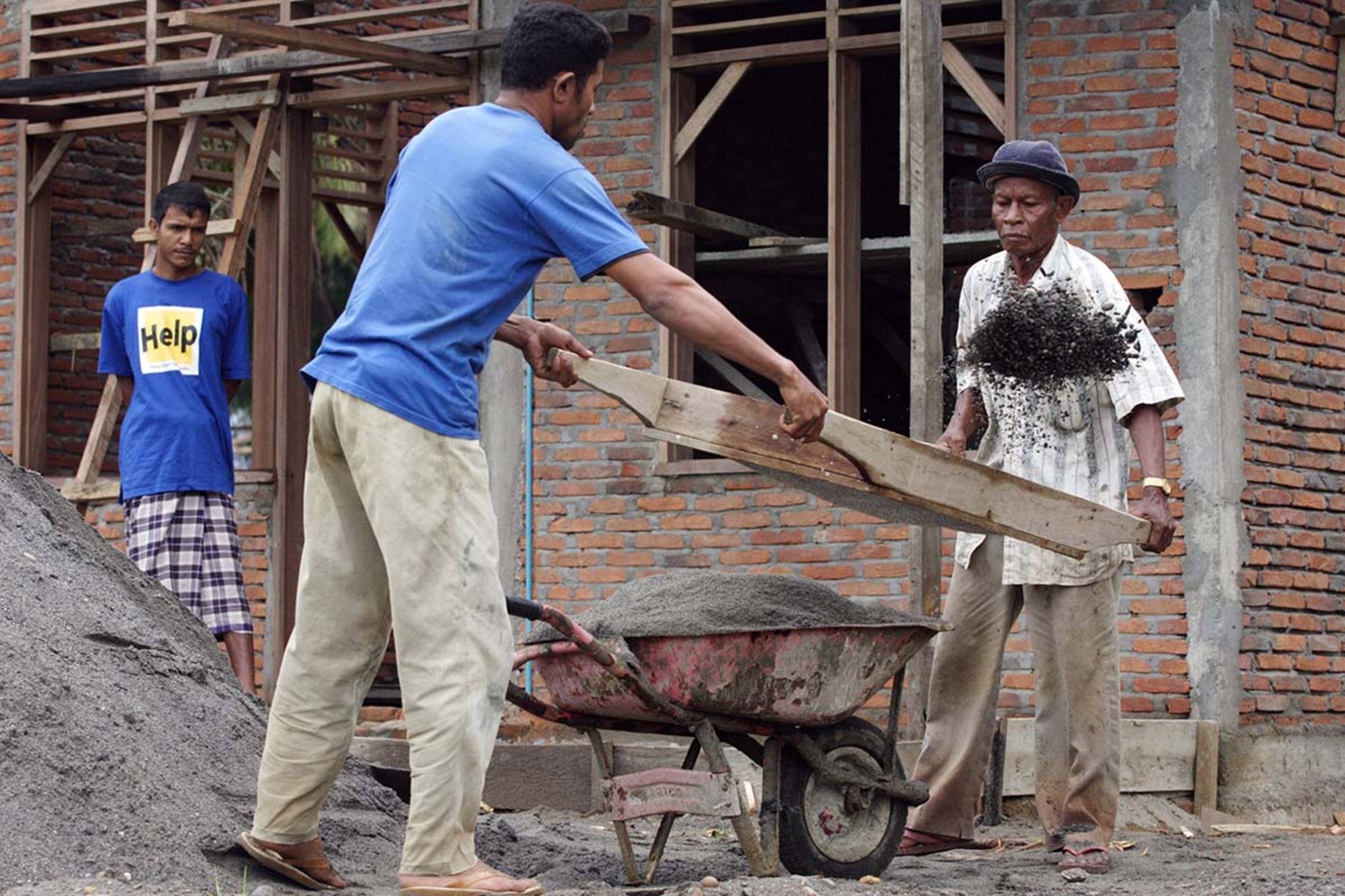 Help-Mitarbeitende transportieren Material zum Wiederaufbau von Gebäuden, die beim Tsunami 2004 zerstört wurden.