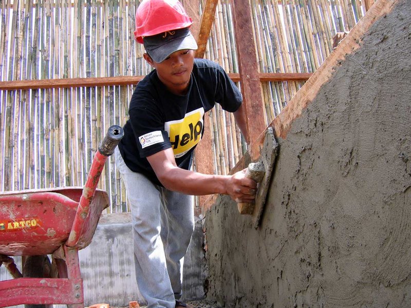 Ein Help-Mitarbeiter in Indonesien verputzt die Mauer eines Gebäudes, das beim Tsunami 2004 zerstört wurde.