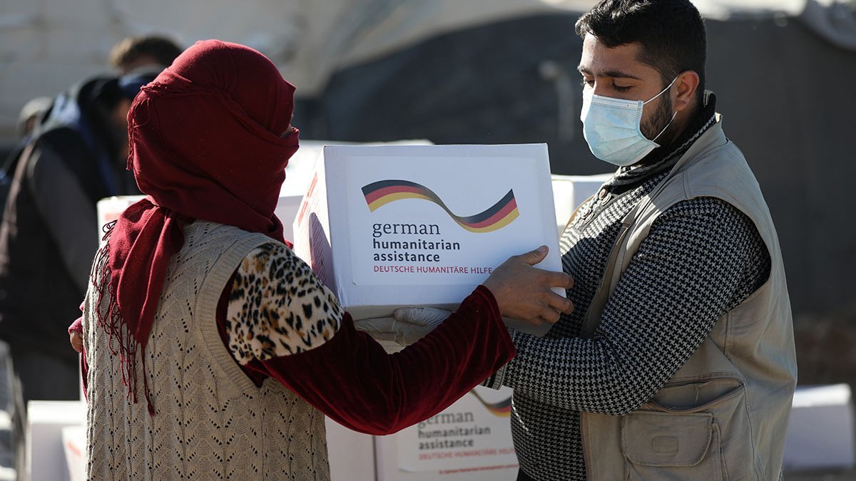 Ein Helfer verteilt Hilfsgüter an syrische Geflüchtete