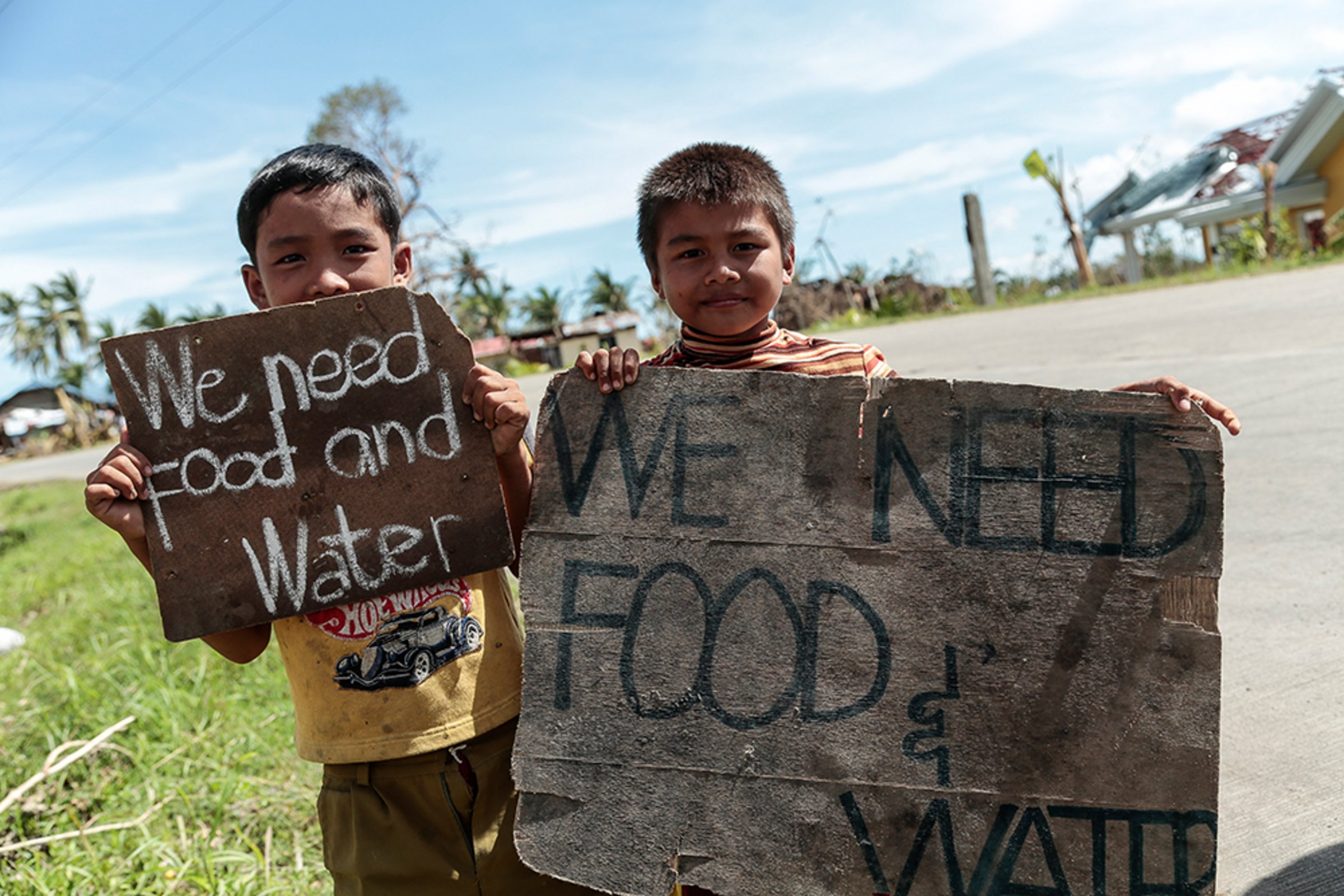 Philippinische Kinder halten Schild mit Bitte zur Hilfe hoch