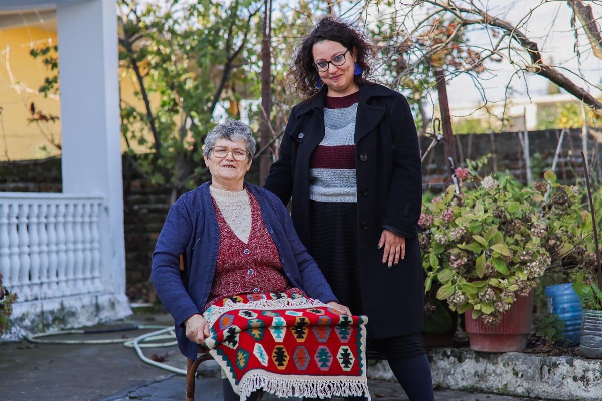 Zwei Frauen in Albanien zeigen stolz einen Teppich, den sie mit Unterstützung von Help gewebt haben.