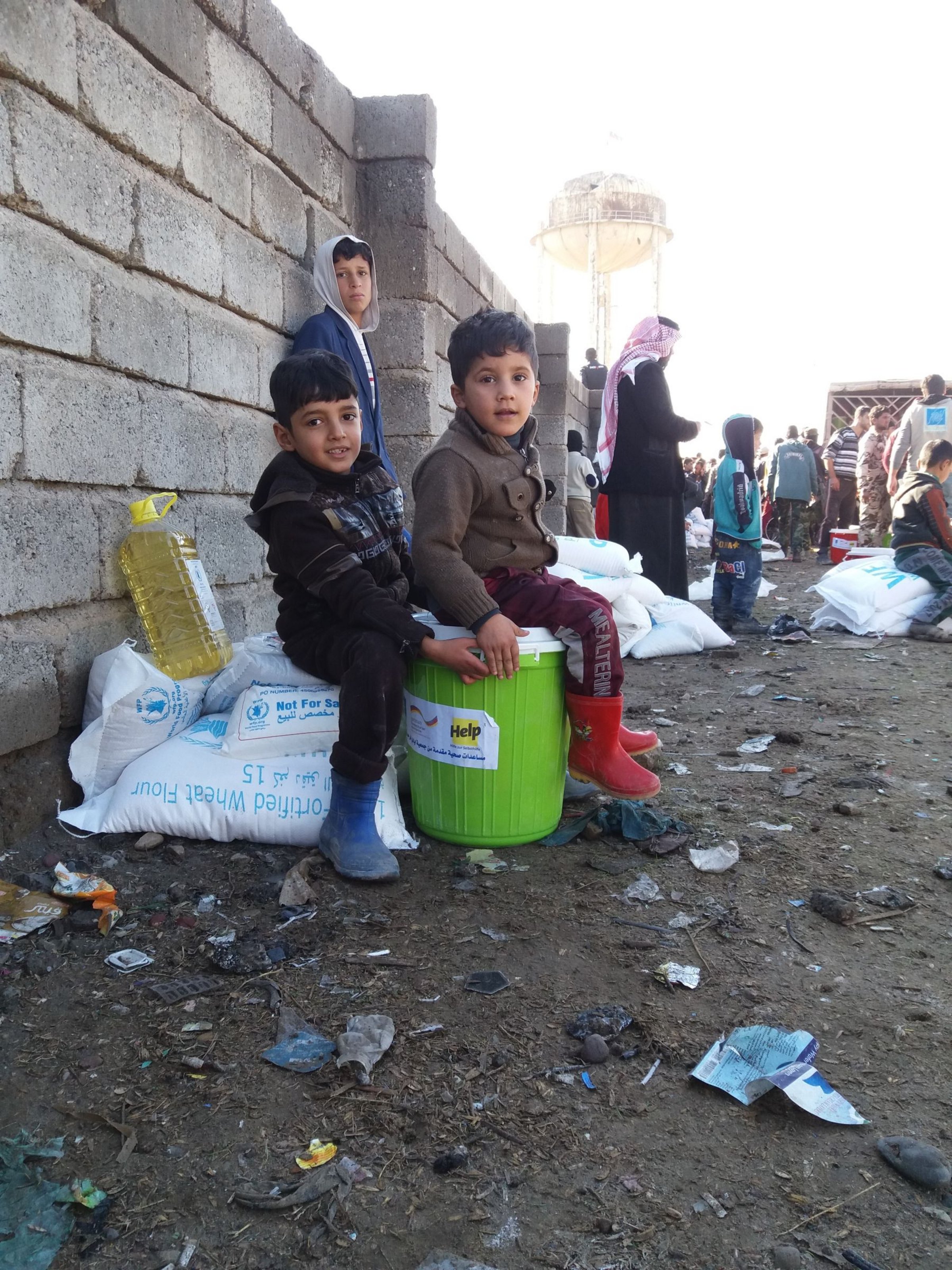 Irakische Flüchtlingskinder sitzen auf Hilfspaket
