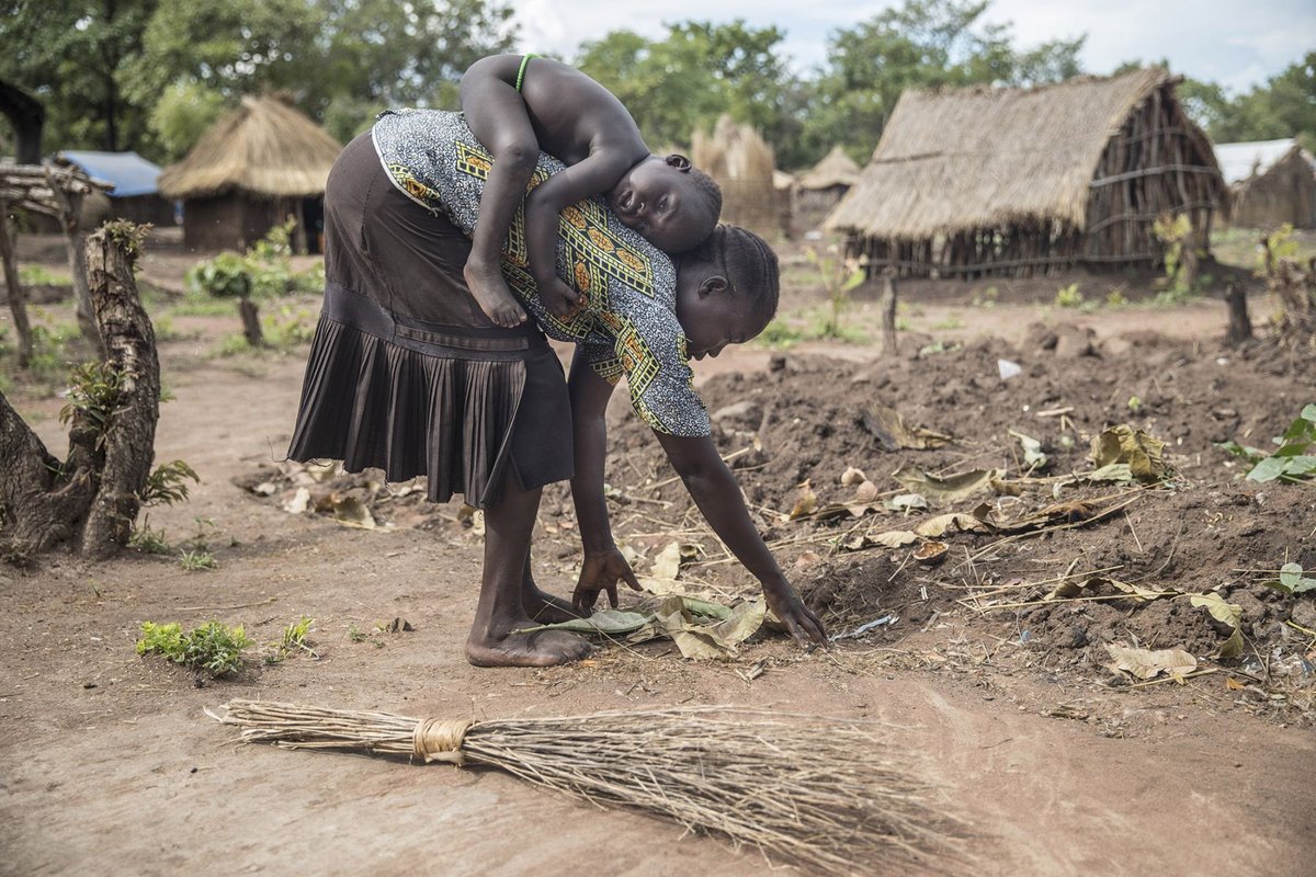 Spenden für Afrika: Eine südsudanesische Mutter bei der Ernte mit ihrem Kind auf dem Rücken
