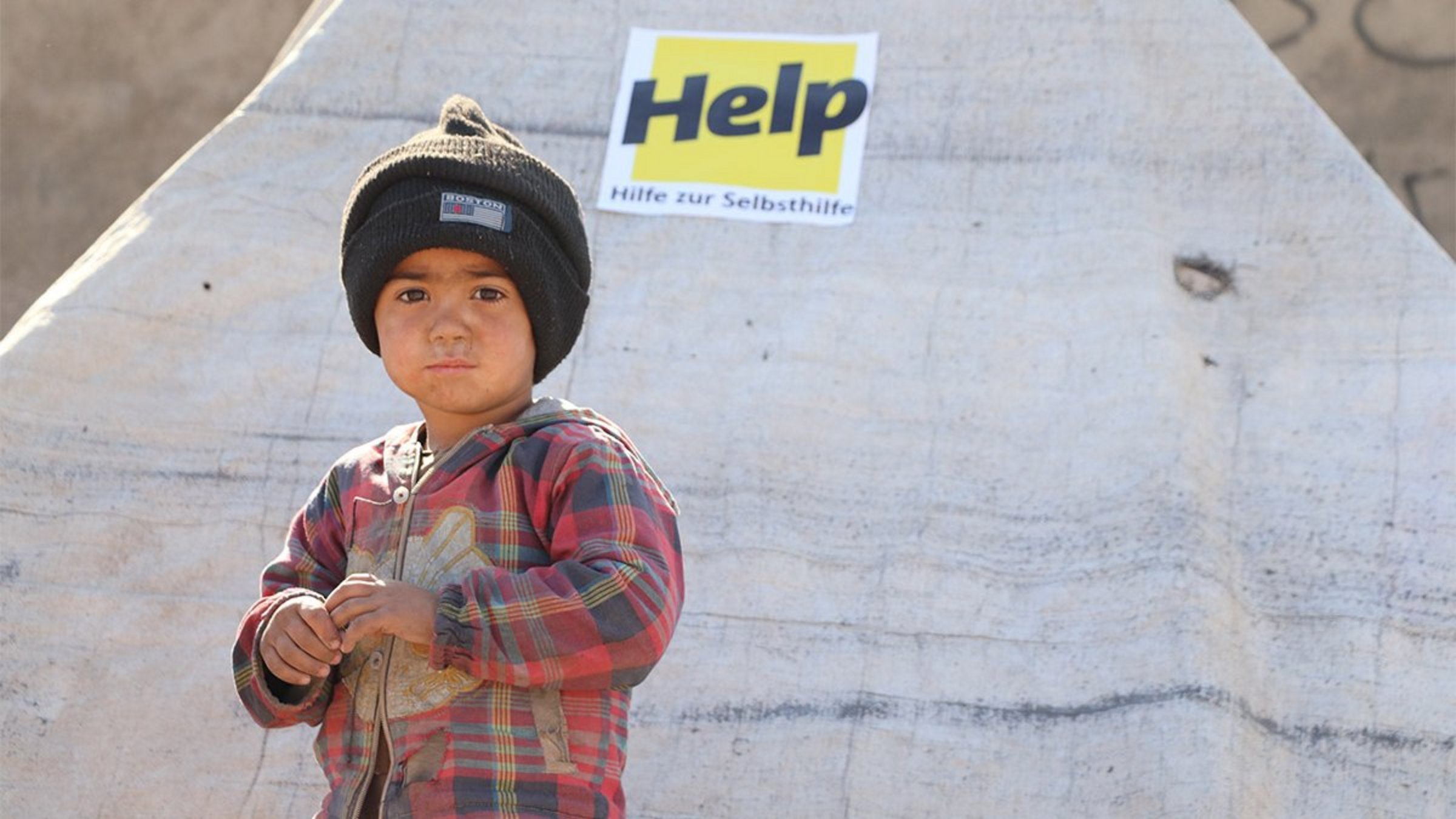 Ein geflüchteter Junge steht vor einem Flüchtlingszelt am Rande der Stadt Herat.