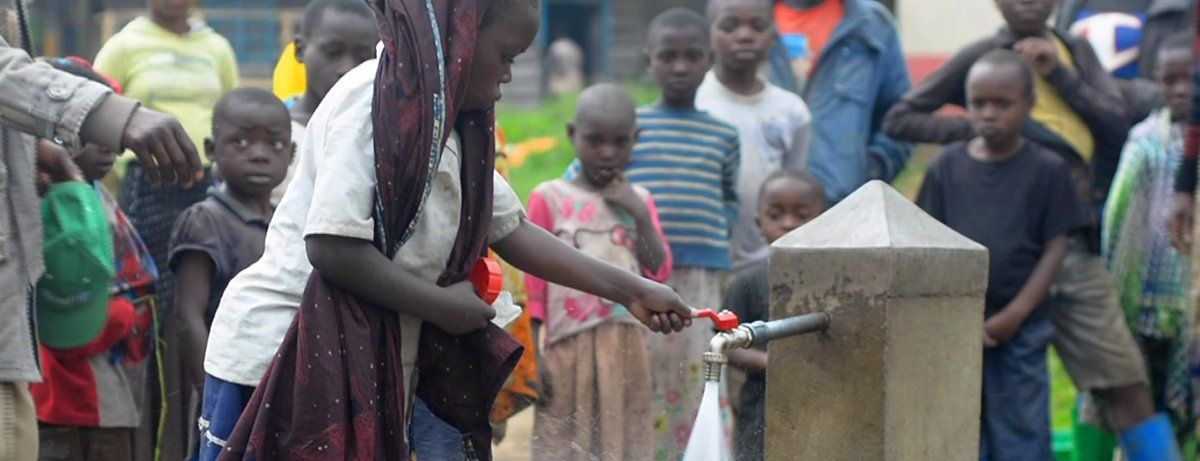 Ein Mädchen aus dem Kongo zapft sauberes Trinkwasser aus einem von Help gebauten Brunnen.