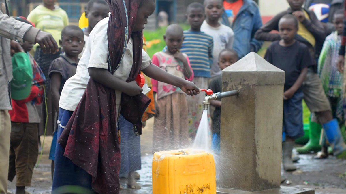 Ein Mädchen aus dem Kongo zapft sauberes Trinkwasser aus einem von Help gebauten Brunnen.