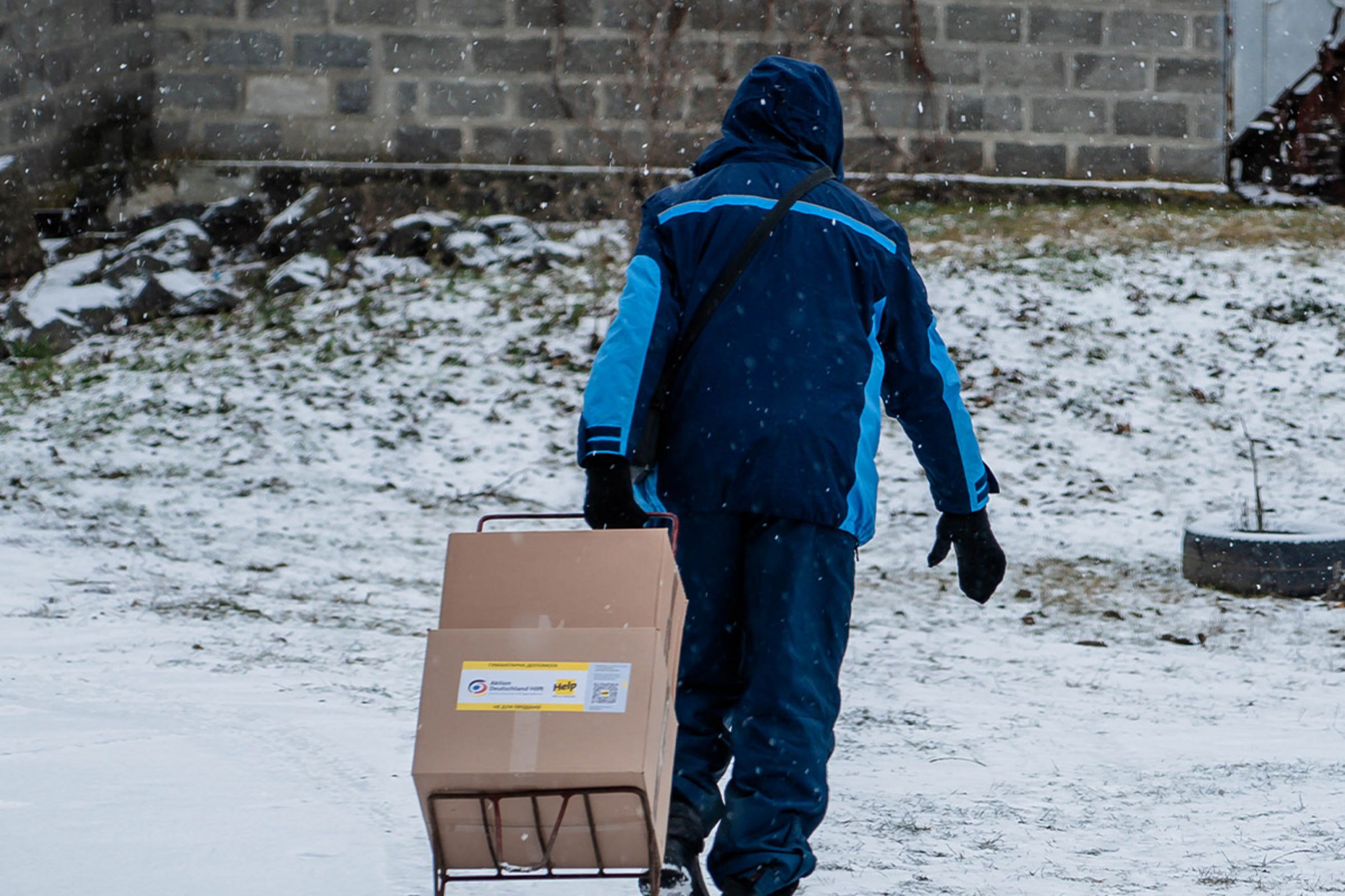 Ein Mann zieht Hilfspakete hinter sich durch den Schnee